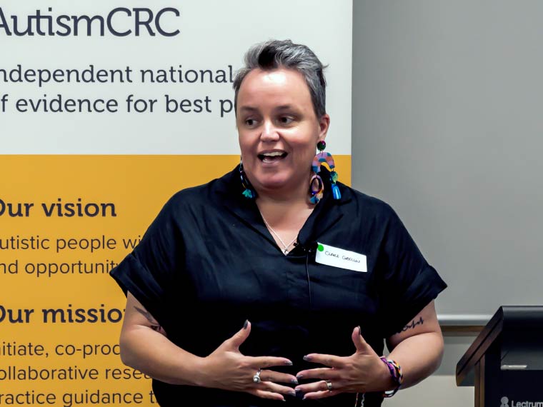 Clare speaking in front of an Autism CRC banner.