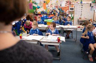 Teacher standing at the front of a classrom with attention students