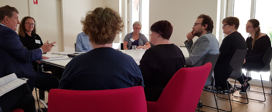 A group of people in business clothes sitting at a table and discussing something.