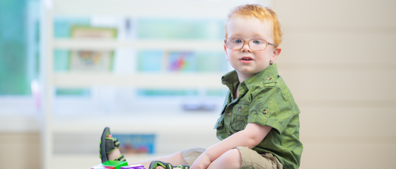 A small child looks at the camera, sitting down amongst blocks