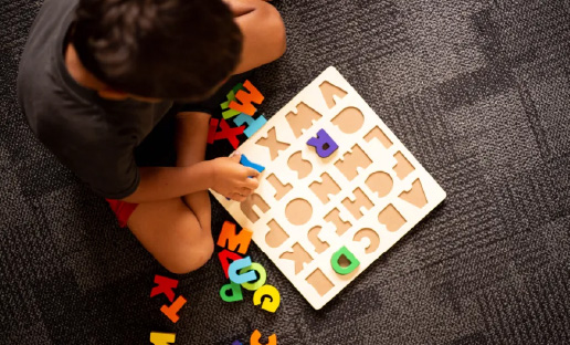 A young child sitting on the floor and working on an alphabet puzzle
