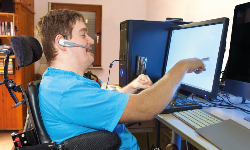 A young adult in a wheelchair using a communication device via a computer touch screen
