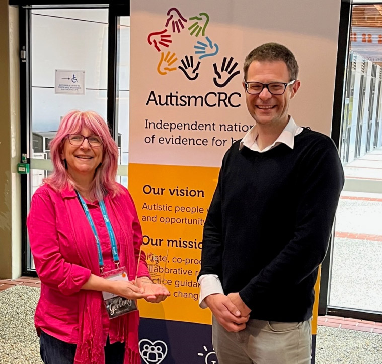 Professor Sandra Jones holding an award, standing next to Professor Andrew Whitehouse