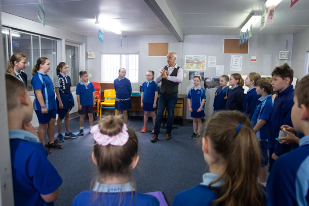 Classroom with students standing around a teacher.